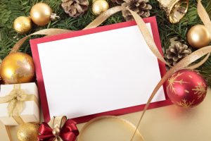 Blank Christmas card or invitation with red envelope surrounded by ribbons and decorations. Space for copy.